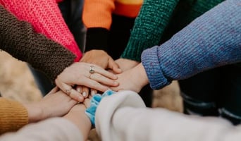 group of people in a huddle with their hands in the center