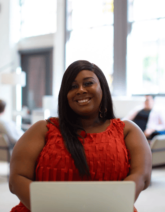 Lady smiling while working on a laptop 