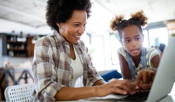 Woman and young girl working together on a laptop