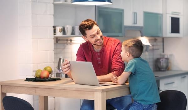 Image of father and son sitting at a kitchen table with a laptop