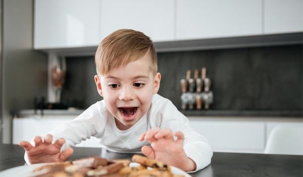 little boy excited reaching for the cookie plate
