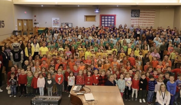 Image of students in a music room celebrating their STEAM day all wearing different color shirts