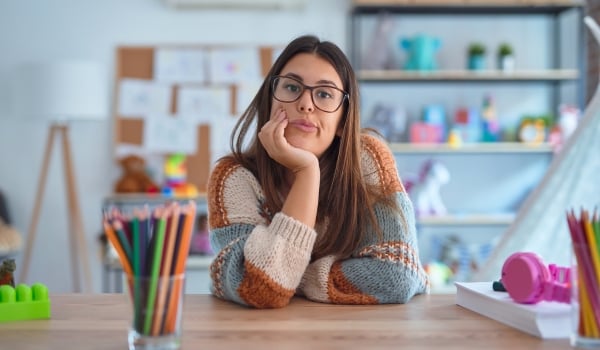 Image of woman in a classroom with her hand on her chin thinking