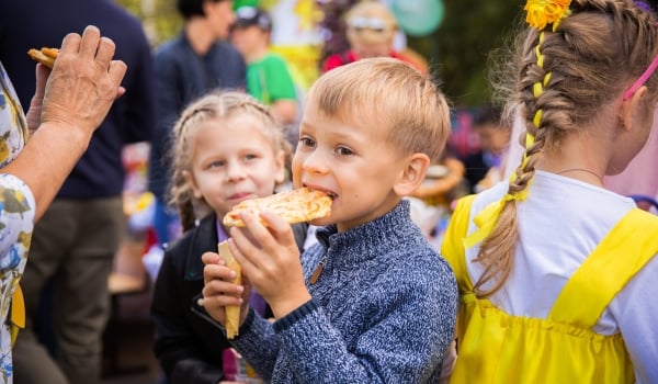 image of a boy eating a cookie and other people behind him at the bake sale