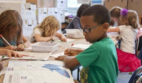 boy sitting at a table in school doing work