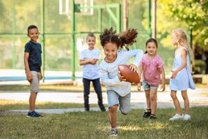 Children outside running with a football