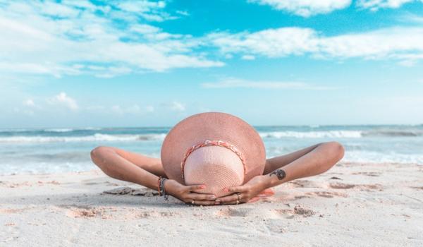 woman in brown sun hat laying on sand