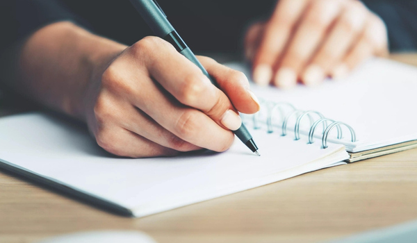 person writing on a pad of paper