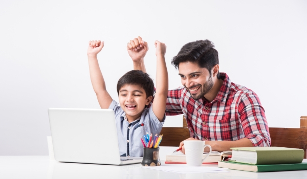 Image of dad and son looking at a laptop with arms in the air celebrating