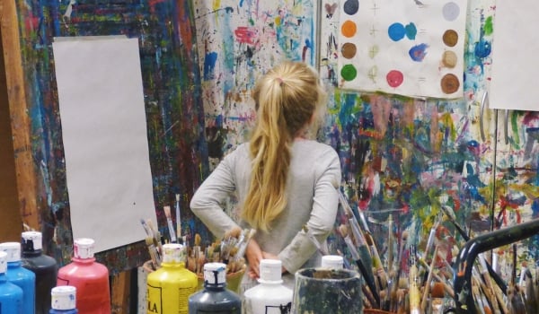 Image of girl in art class looking at paint and art on the wall