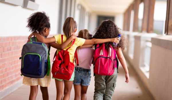 image of four young girls walking into school with their arms around eachother