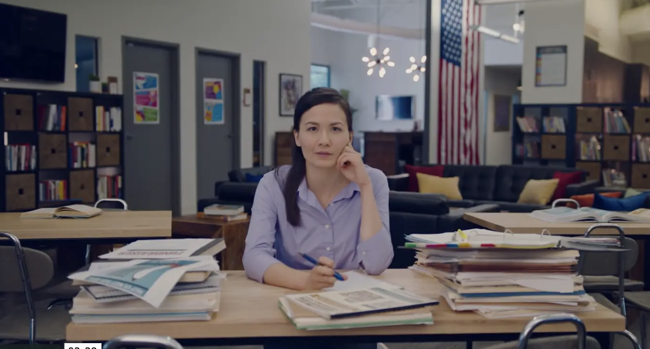 A woman sits at a desk and ponders.