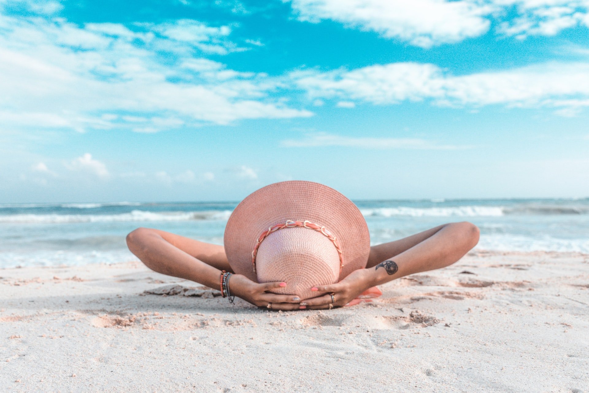woman in brown sun hat laying on sand